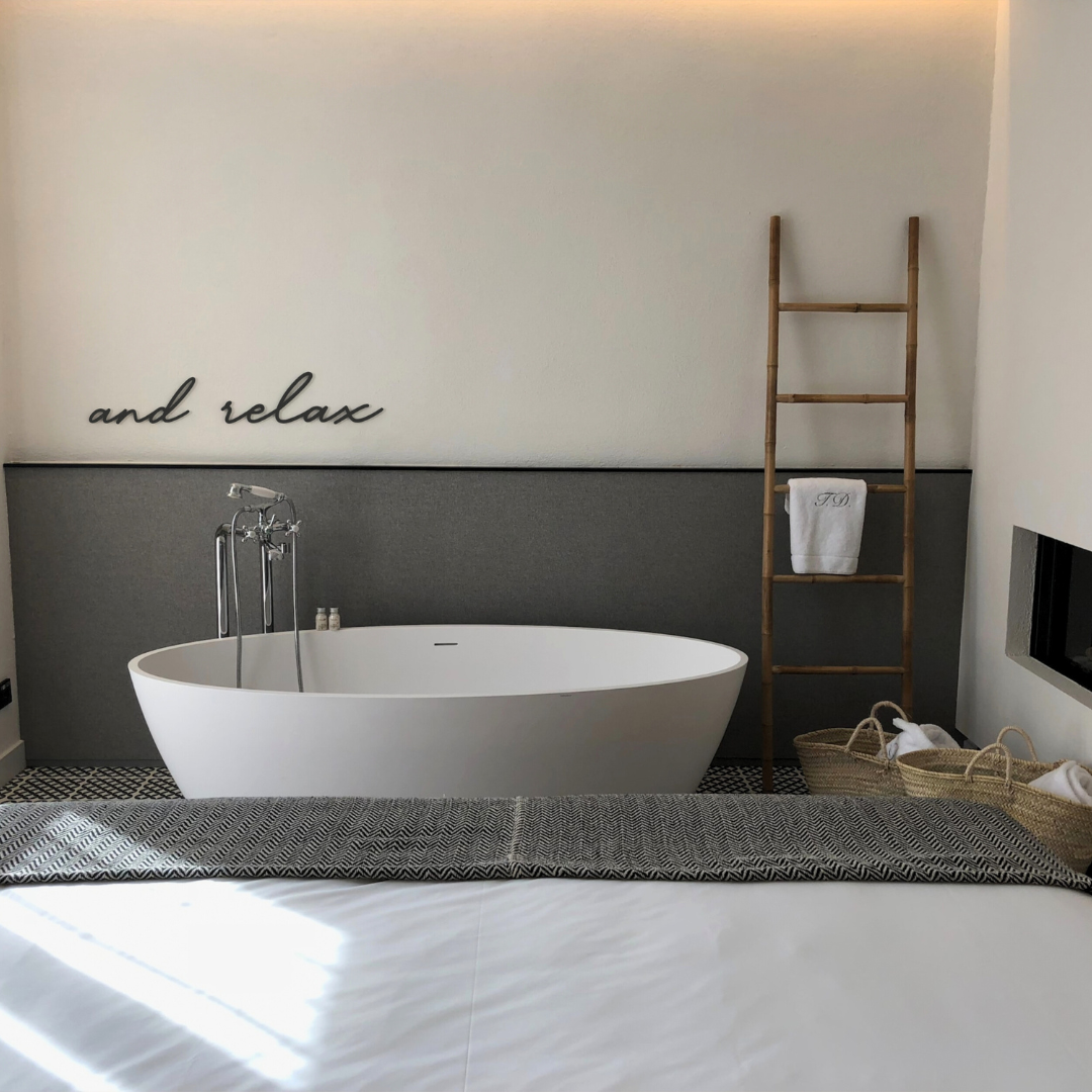 black and relax metal sign hangs on wall in bathroom