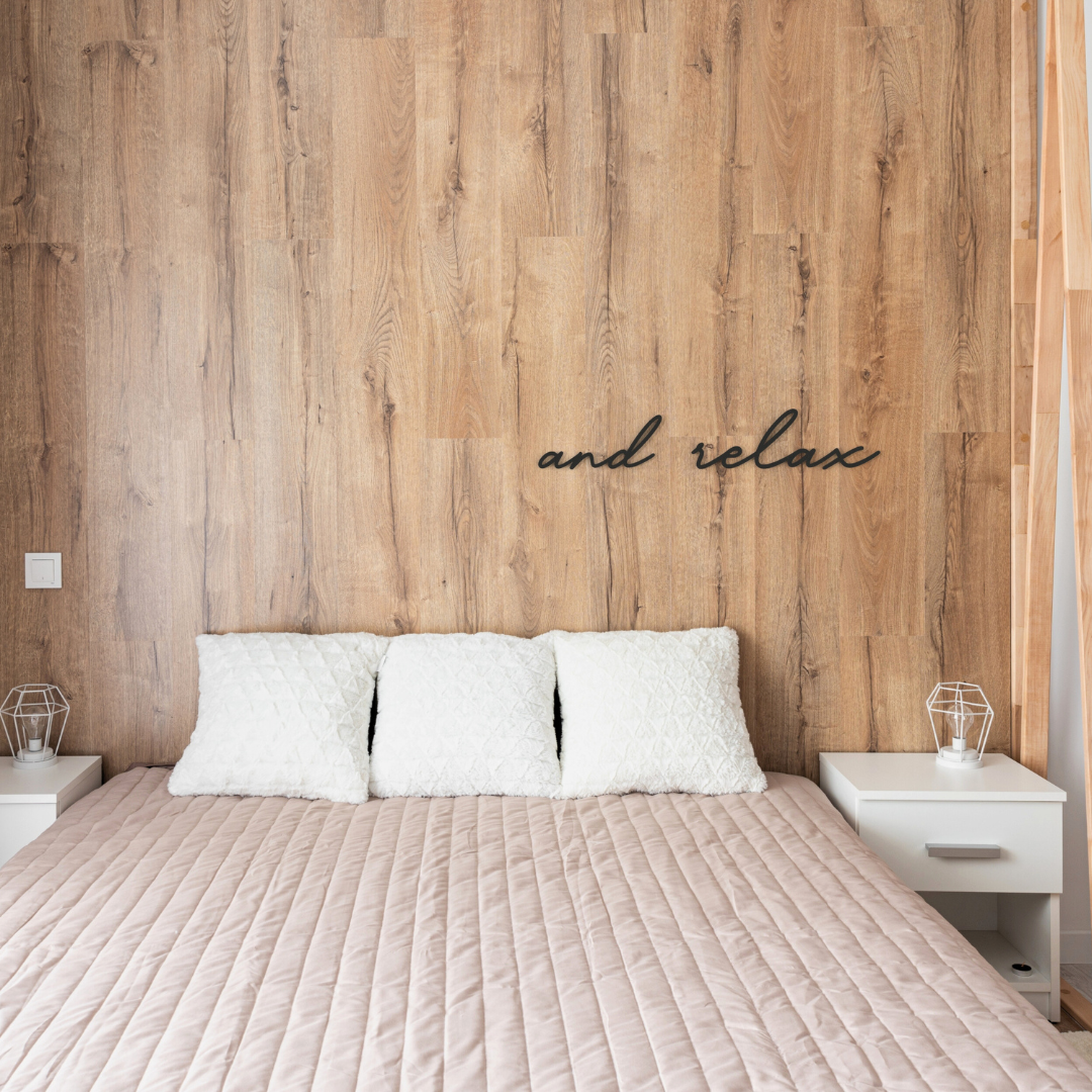 black and relax metal sign hangs on wall in bedroom