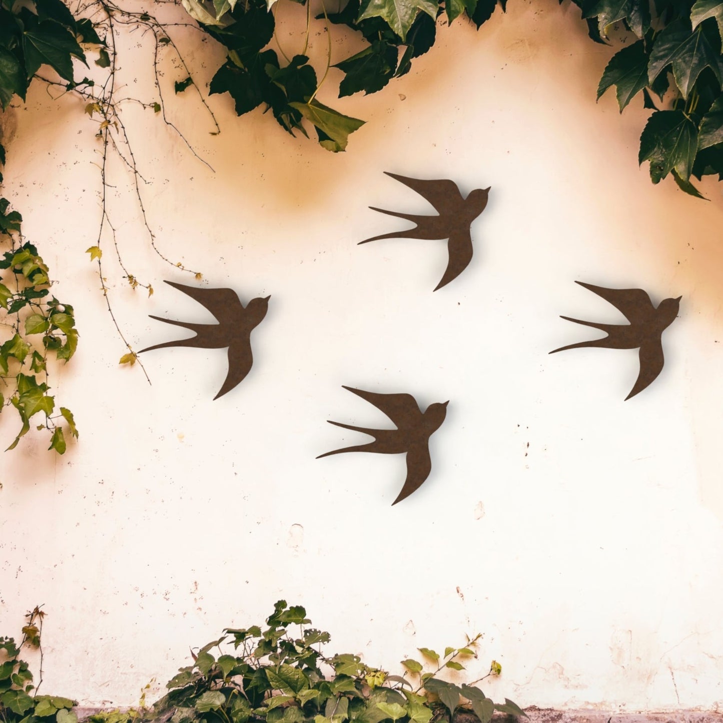 rusty brown swallows set of four hanging on wall with ivy in garden