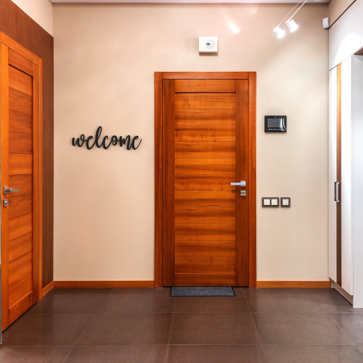 black welcome metal sign hangs on wall in hallway