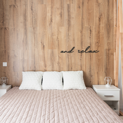 black and relax metal sign hangs on wall in bedroom