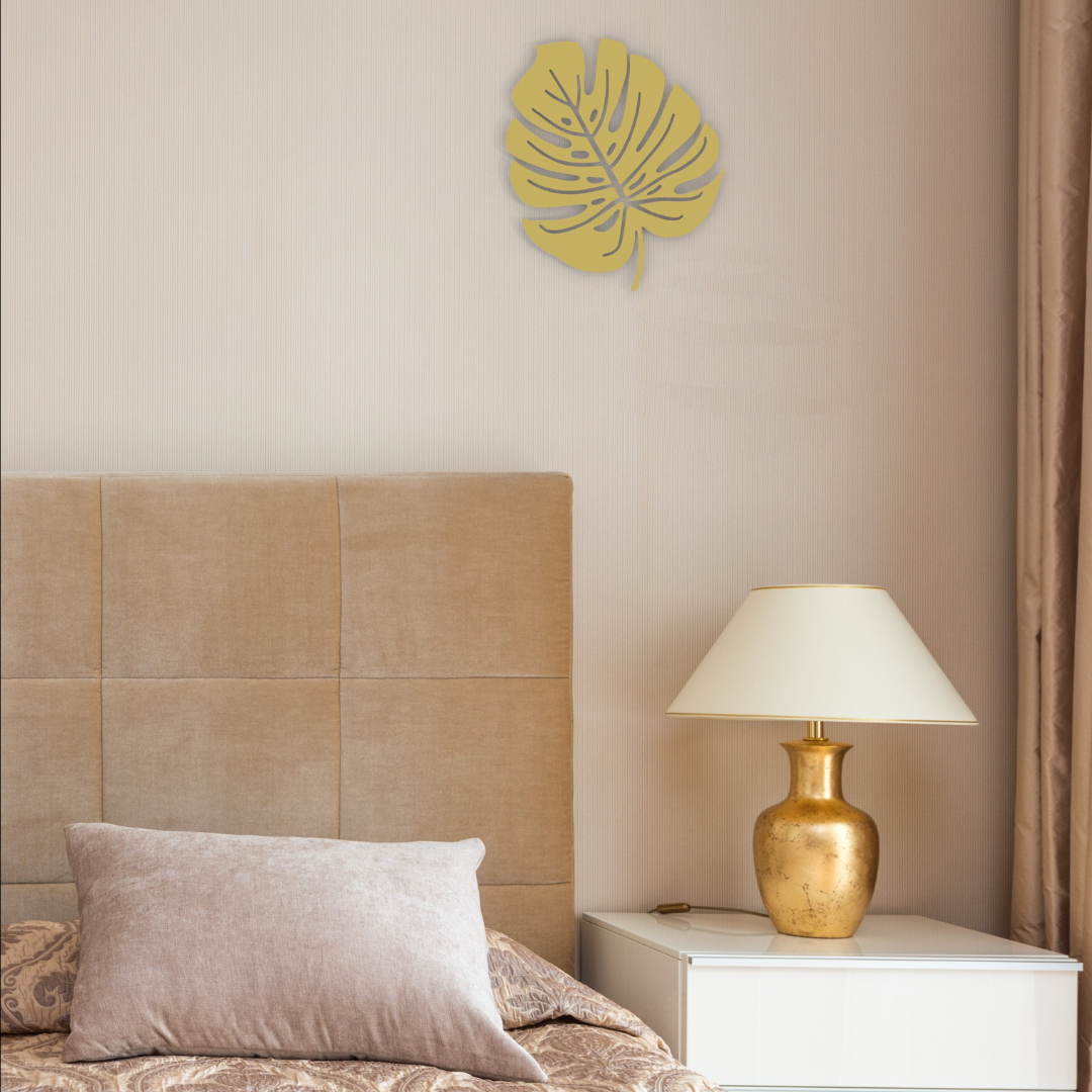 golden monstera leaf metal wall art on wall in bedroom