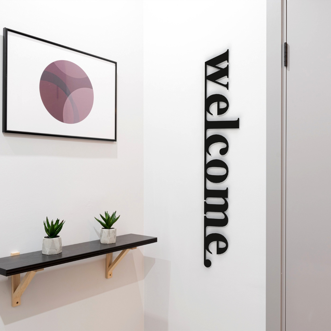 black welcome metal sign on wall in hallway