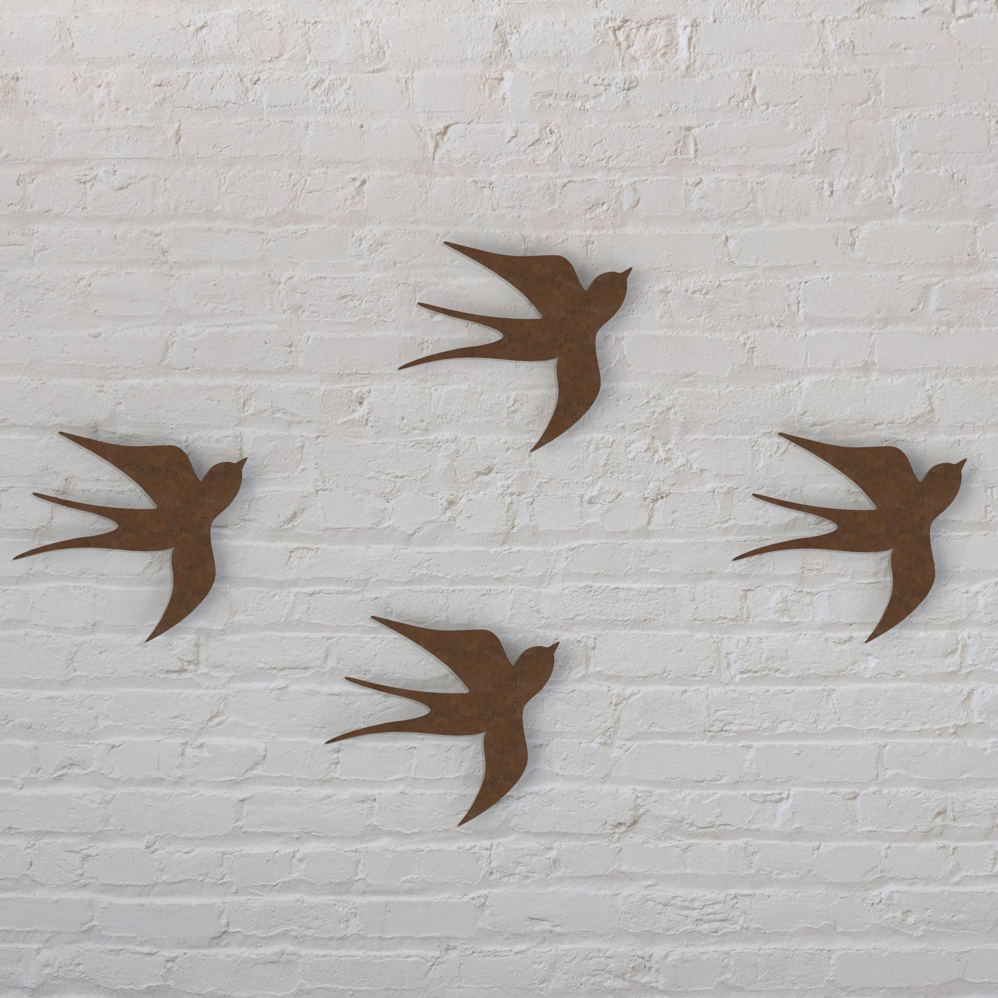 rusty brown swallows set of four hanging on a white brick wall