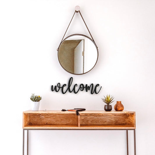 black welcome metal sign hangs on wall in hallway